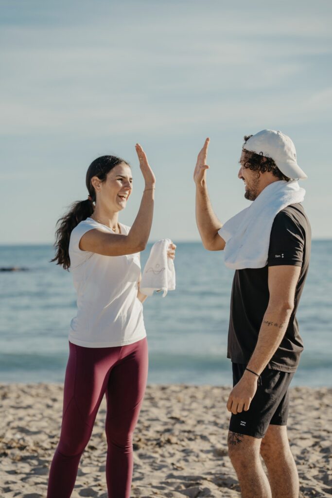 Two people giving each other a high five on a beach