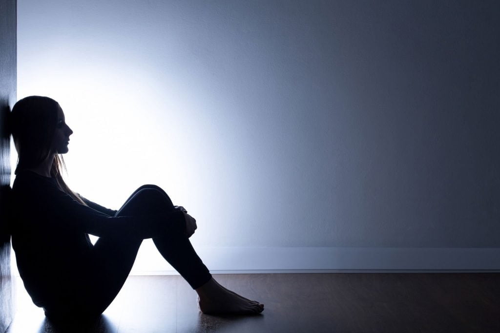 person sitting on the floor with their back to the wall