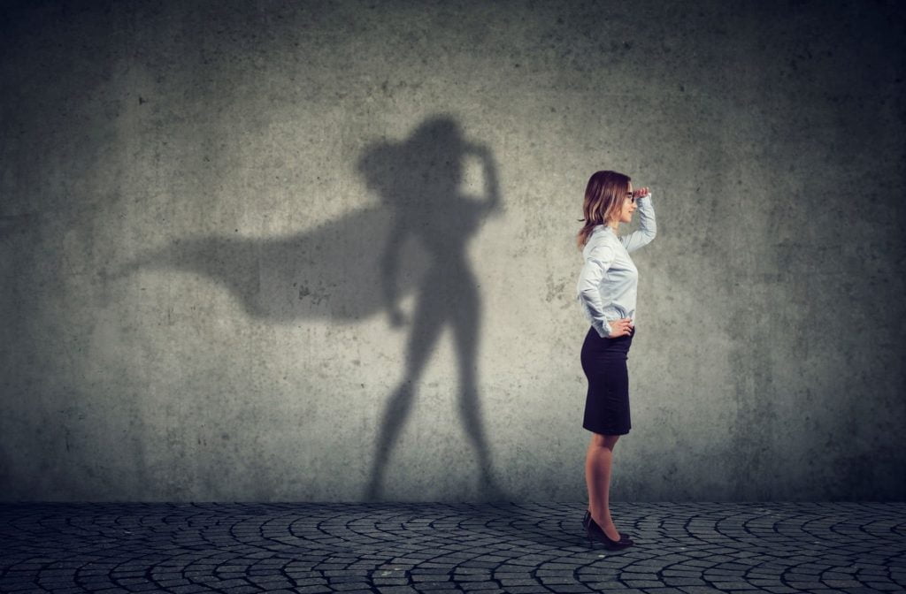 woman standing and her shadow appearing as a superhero