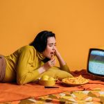 A woman binge eating while she watched a show.