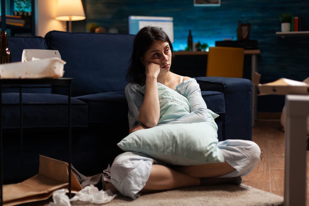 sad woman sitting on the floor in front of a couch