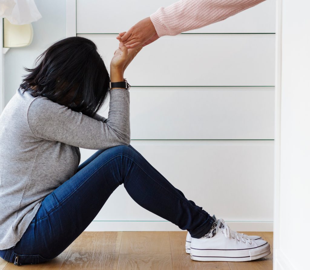 woman sitting on the floor with someone helping her to get up