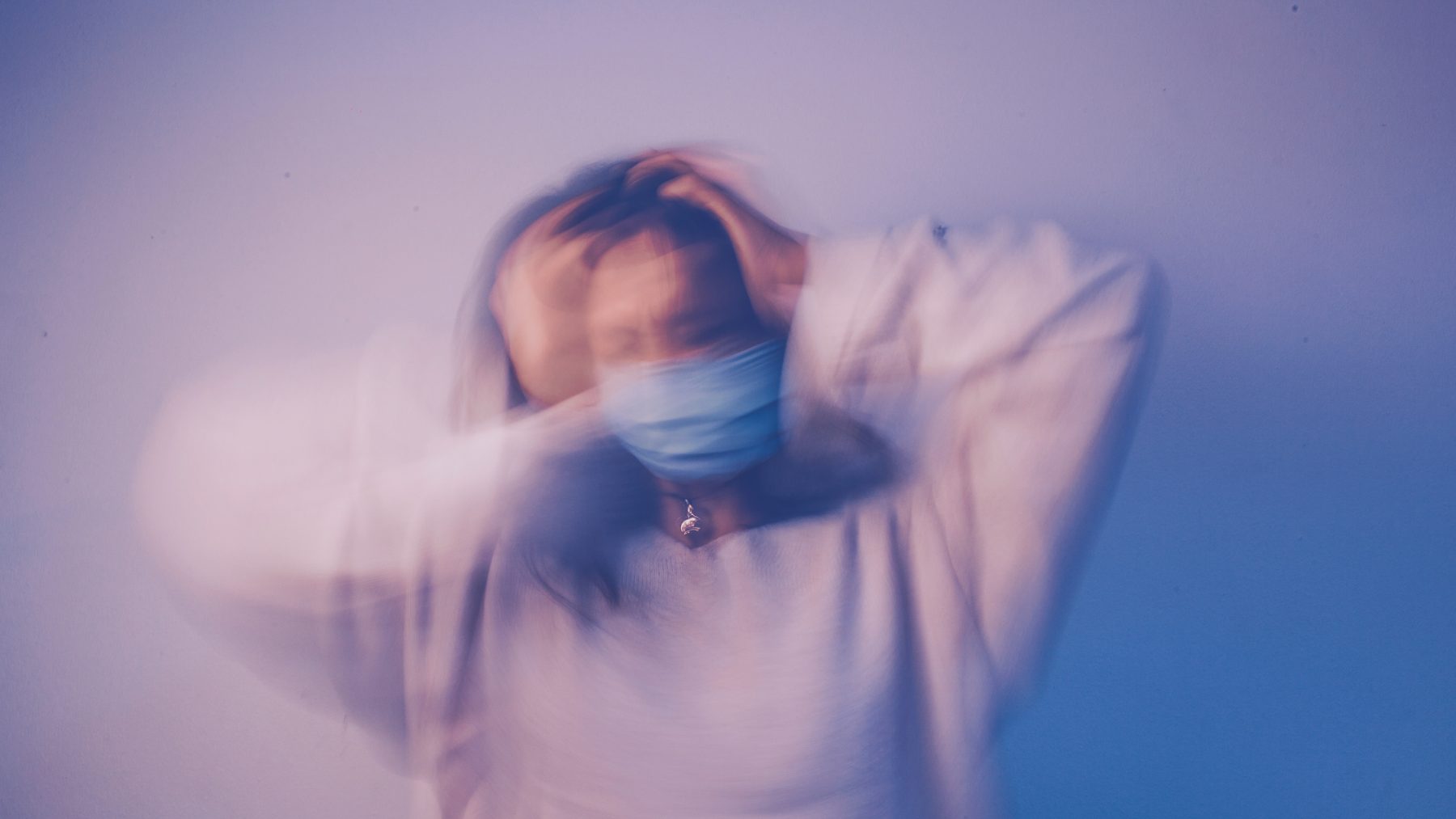 A blurry picture of a woman with her hands on her head.
