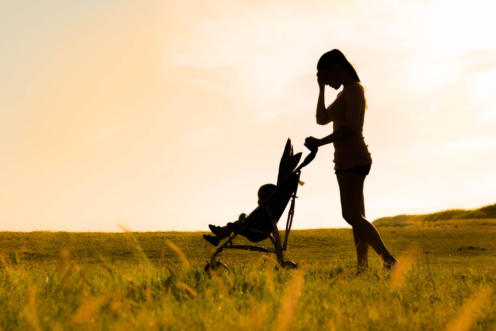Mother with post-partum depression in a green field with her baby